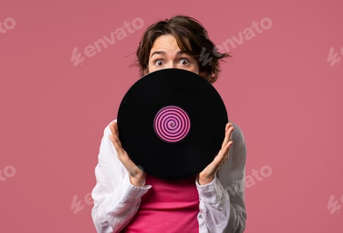 Preview: Positive short haired woman with vinyl record disc on pink. Hobby, music lover, collection