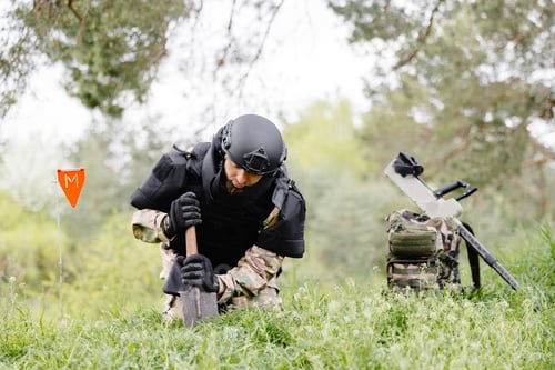 Preview: A man in a military uniform and a bulletproof vest works in the forest to demine the territory