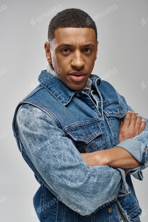 Preview: handsome emotional african american man in denim outfit posing on white backdrop, fashion concept
