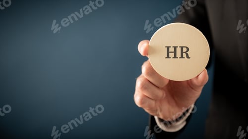 Preview: Businessman, an employer, holding a wooden cut circle wit an HR sign on it
