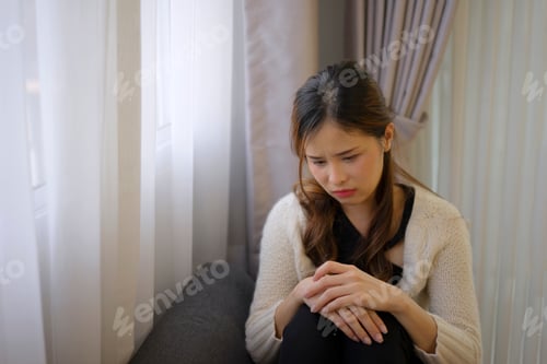 Preview: Pretty woman with sad emotion sit on sofa.
