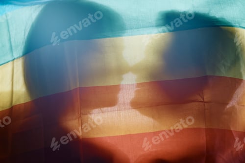 Preview: Gay women in love kissing behind LGBT flag.