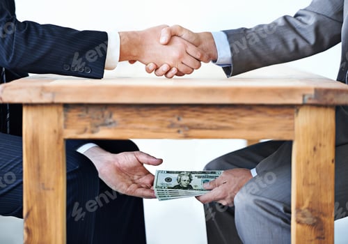 Preview: Cropped shot of two businessmen shaking hands while money passes hands under a table