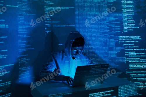 Preview: Concentrated young man in hooded shirt using computer against dark background