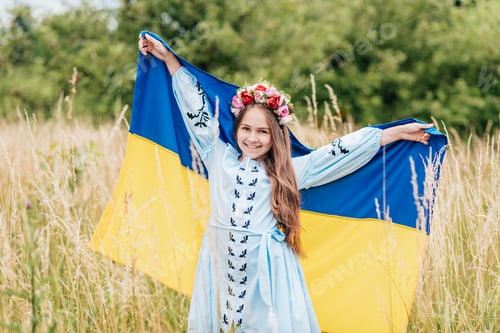 Preview: Ukrainian child girl in embroidered shirt vyshyvanka with yellow and blue flag of Ukraine in field.