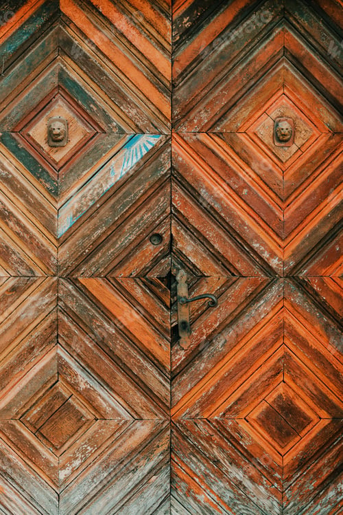 Preview: Old worn wooden door with symmetrical diamond pattern and rusty handle