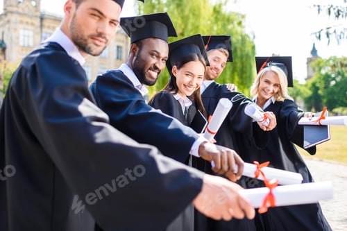 Preview: young graduated students holding rolled diplomas