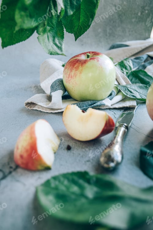 Preview: Freshly harvested ripe green red organic apples over napkin or towel and knife on table.