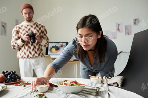 Preview: Asian Woman Arranging Food While Man Photographing in Background