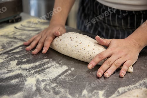 Preview: Closeup of baker's hands rolling out the bread dough on the table