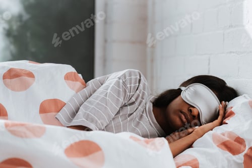 Preview: Young African female in a white eye mask sleeping in her bed in the morning