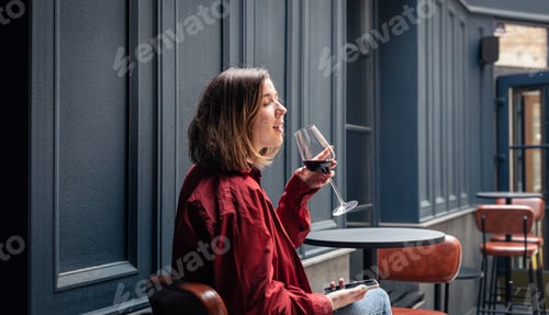 Preview: A young woman with a glass of wine on the terrace of a restaurant.
