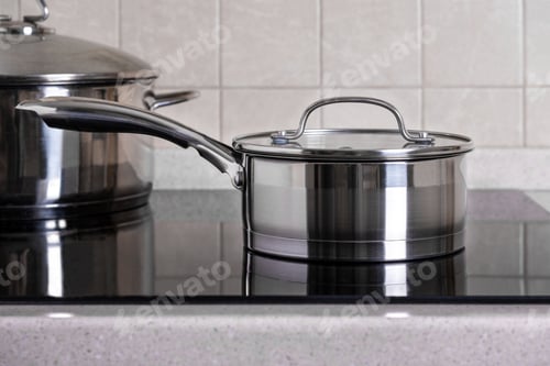 Preview: Ladle and large saucepan stand on modern stove with glass-ceramic hob