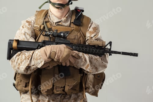Preview: Soldier in military uniform holds rifle standing indoors with neutral background