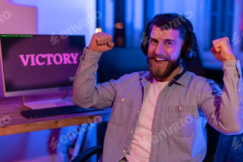 Preview: Gamer young man celebrates victory with fists raised
