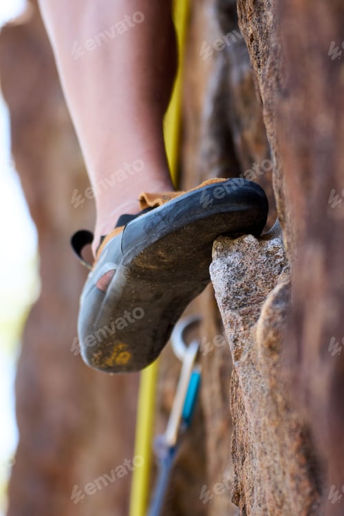 Preview: Vertical image of a rock climber's foot on a protruding rock