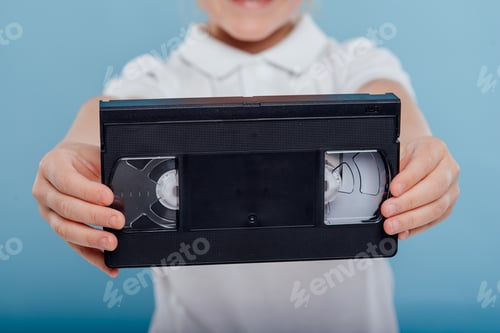 Preview: video tape in child hand, isolated on blue background