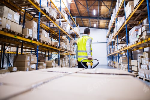 Preview: Male warehouse worker pulling a pallet truck.