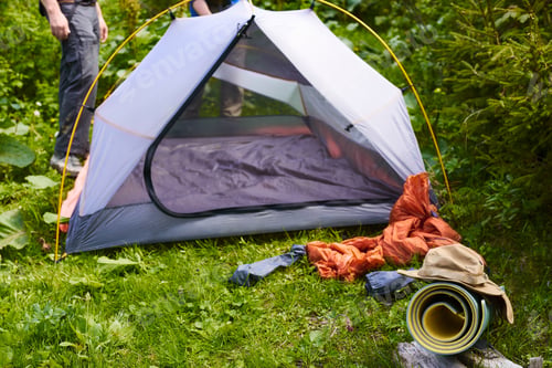 Preview: tent in camp. tourists setting up tent in camping in green forest. summer vacation outdoors