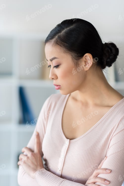 Preview: Portrait of pensive young asian woman standing with crossed arms and looking down