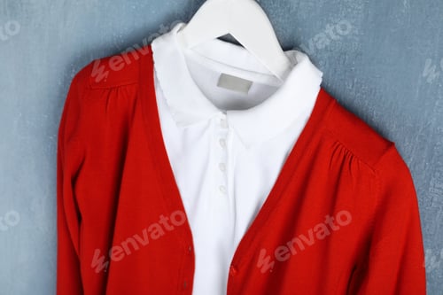 Preview: Shirt and jumper hanging on blue wall. School uniform