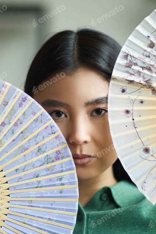 Preview: Portrait of Young Asian Woman Looking at Camera Holding Decorative Fans