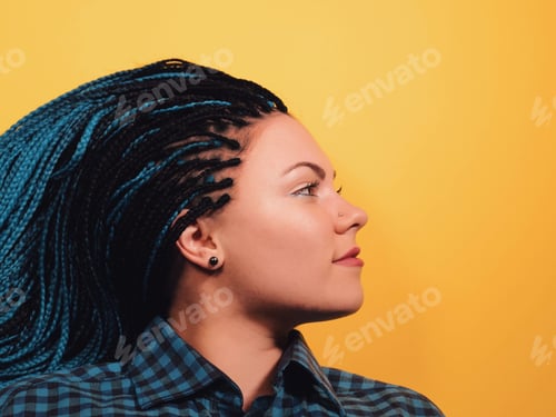 Preview: Beautiful young girl with african blue braids looks at the camera