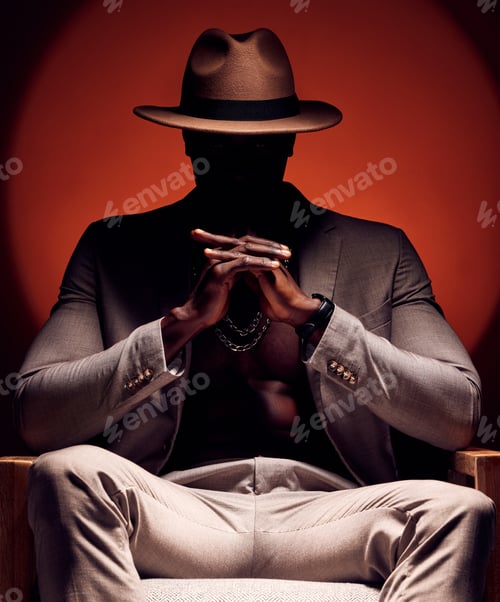 Preview: Stylish, fashionable and trendy man in silhouette sitting in a dark room with a red studio backgrou