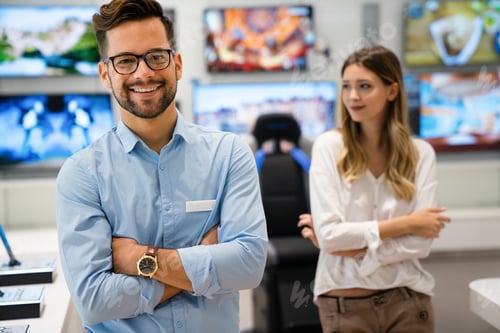 Preview: Happy seller man helping to woman to buy a new digital smart device in tech store