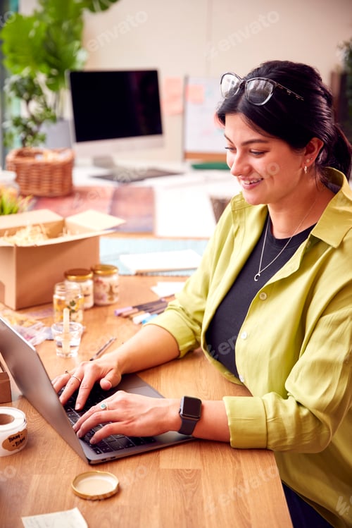 Preview: Woman Running Online Business Making Boutique Candles At Home Working On Laptop