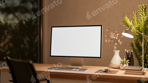 Preview: Blank screen computer with lamp and flower vase on wooden drawer table and chair in dim lit room.