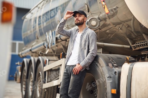 Preview: Touching the black cap. Young truck driver in casual clothes