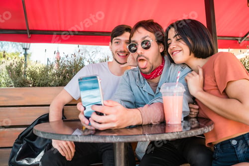 Preview: Three young friends taking a selfie with phone.