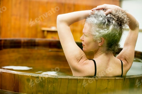 Preview: Mature woman with hands in hair in hot tub at eco retreat