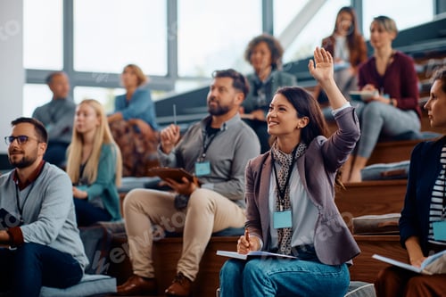 Preview: Female entrepreneur raising a hand to ask a question while attending business seminar.