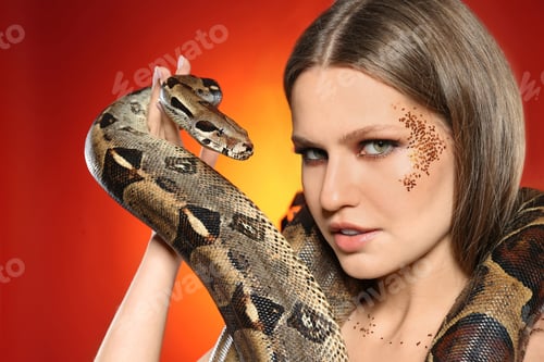 Preview: Beautiful woman with boa constrictor on bright colorful background, closeup