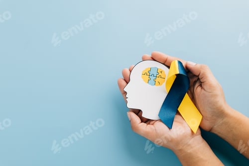 Preview: Hands holding a head with puzzle pieces and a ribbon. Celebrating Down Syndrome Day