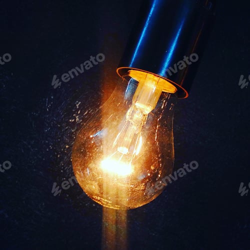 Glowing Lightbulb Against Dark Textured Background