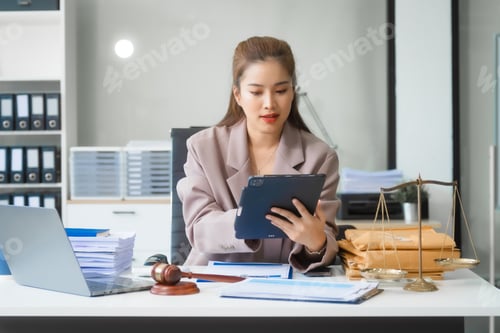 Preview: Asian businesswoman in formal attire works on laptop, on corporate law and marketing strategy.