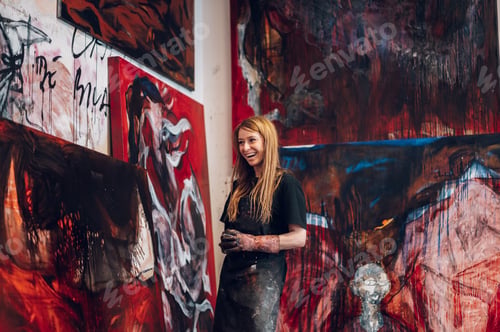 Preview: Young redhead woman painter standing by her art masterpiece on a big canvas