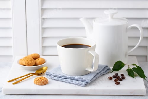 Preview: Black Coffee in Mug with coffee pot on marble cutting board. White background. Close up.