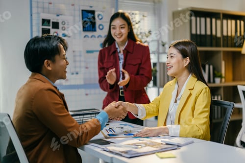 Preview: Business partners celebrating success after signing a contract in a modern office, happy and smiling