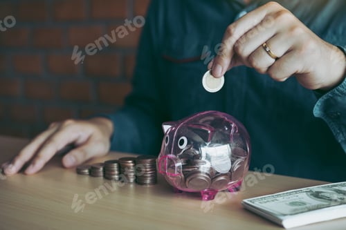 Preview: Men are holding coins dropping to the piggy bank with the concept of saving.