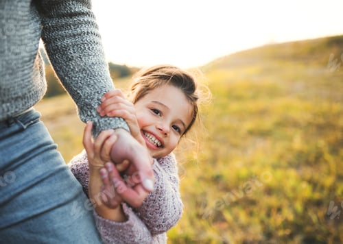 Preview: A small girl with unrecognizable father in autumn nature, having fun.