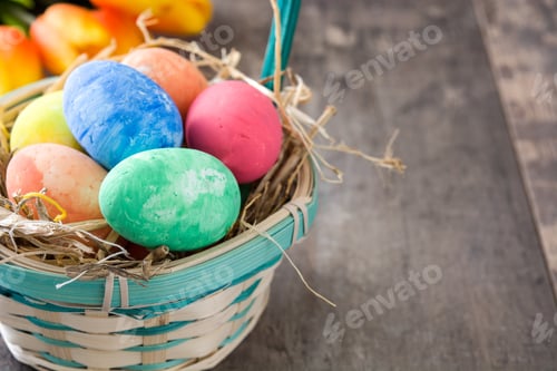 Preview: Colorful easter eggs resting in a basket on rustic wood