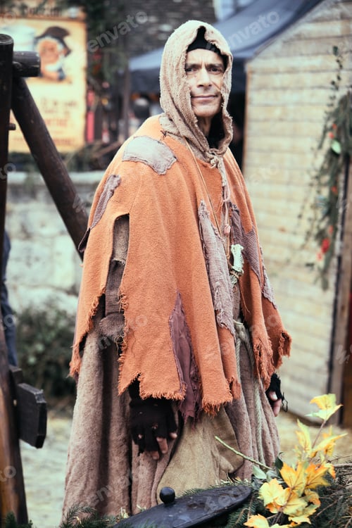 Preview: a person in costume standing outside by some bushes and flowers