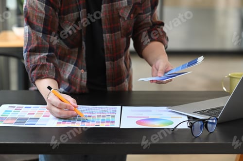 Preview: Young man graphic designer working with color swatches in creative office.