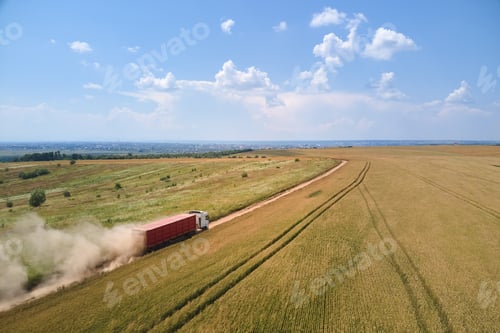 Preview: Aerial view of cargo truck driving on dirt road between agricultural wheat fields making lot