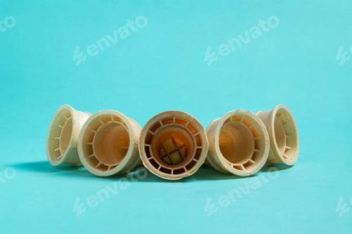 Preview: Five empty wafer ice cream cones arranged in a semi circle on a light blue background. frontal view.