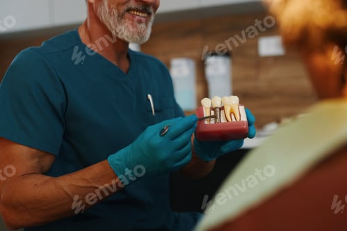 Preview: Smiling Dentist Displaying Dental Implants to Female Patient